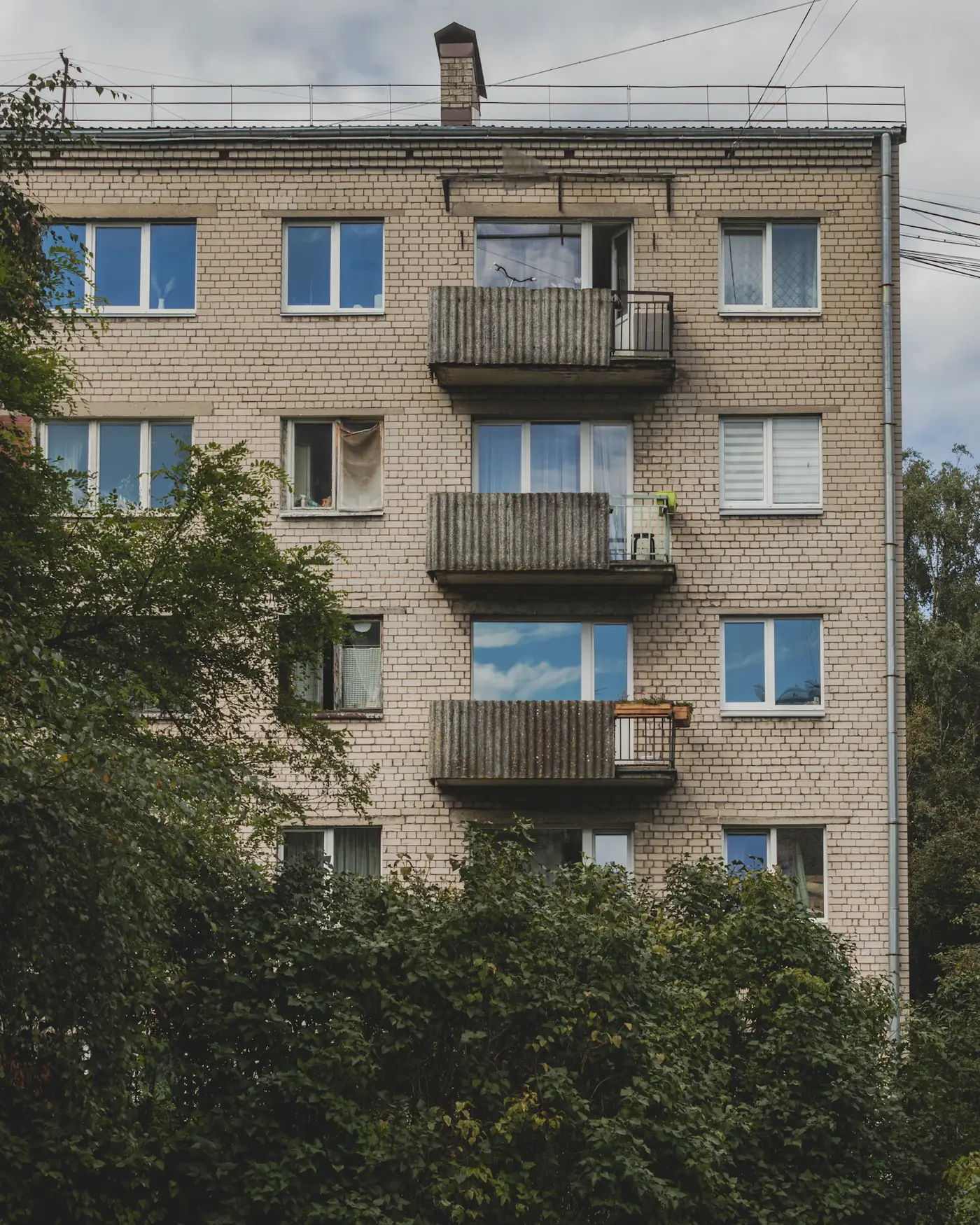 Daudzdzīvokļu māja ar balkoniem un kokiem